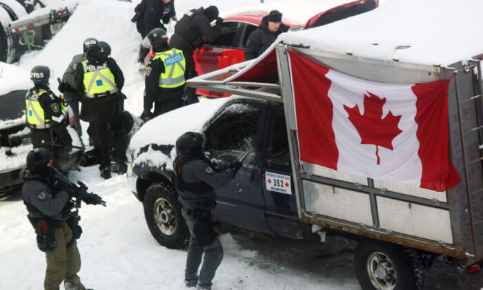 A police officer smashes a truck window as police deploy to remove protesters in Ottawa on Feb. 19, 2022. (Dave Chan/AFP via Getty Images)