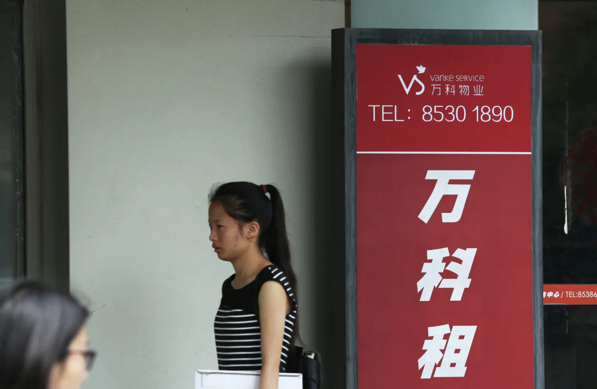 A woman walks past a Vanke Service Center in Beijing on July 6, 2016. (STR/AFP via Getty Images)