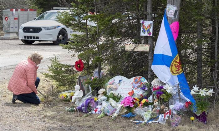 A woman pays her respects to victims of a mass shooting at a roadblock in Portapique, N.S., April 22, 2020. (The Canadian Press/Andrew Vaughan)