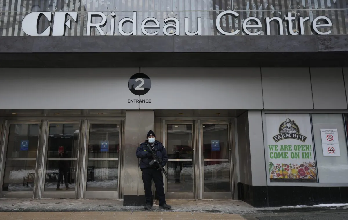 A police officer stands guard outside an entrance to the Rideau Centre in downtown Ottawa on Feb. 22, 2022. (Adrian Wyld/The Canadian Press)