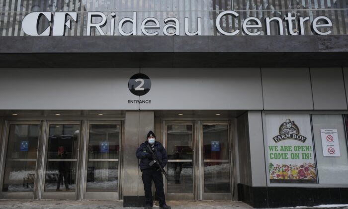 A police officer stands guard outside an entrance to the Rideau Centre in downtown Ottawa on Feb. 22, 2022. (Adrian Wyld/The Canadian Press)