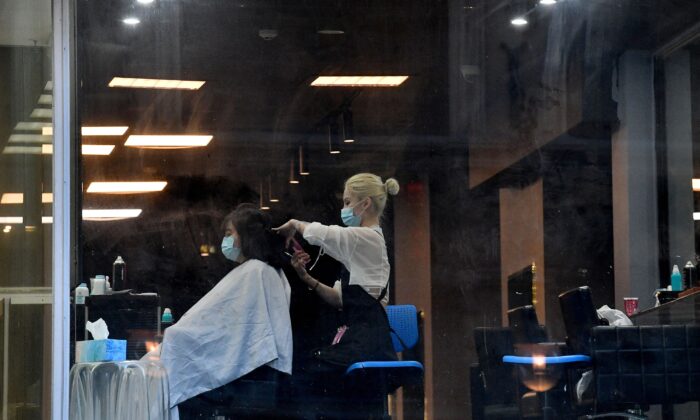 2021 年 6 月 25 日，一名戴着口罩的顾客在澳大利亚悉尼的中央商务区理发。（Saeed Khan/AFP via Getty Images）