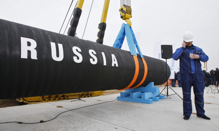 A Russian construction worker speaks on a mobile phone during a ceremony marking the start of Nord Stream pipeline construction in Portovaya Bay some 170 kms (106 miles) north-west from St. Petersburg, Russia, on April 9, 2010. (Dmitry Lovetsky/AP Photo)