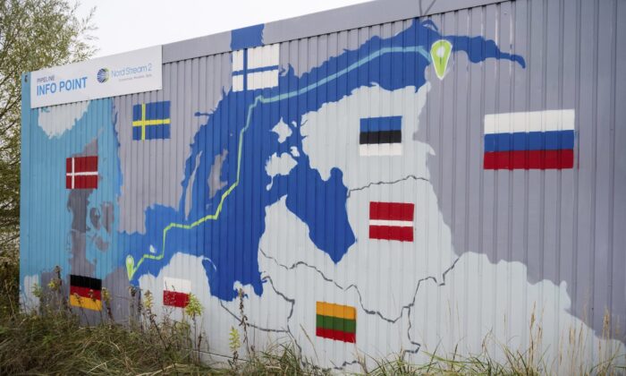 A sign reading "Nord Stream 2 Committed. Reliable. Safe." hangs above a painted map of the Nord Stream 2 pipeline from Russia to Germany at the natural gas receiving station in the Lubmin industrial estate in Lubmin, Germany, on Nov. 16, 2021. (Stefan Sauer/DPA via AP)