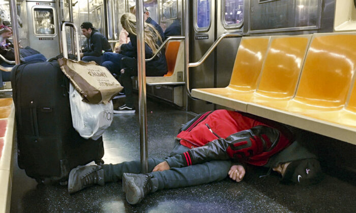 A man sleeps under the seats of a subway car in New York, on Oct. 31, 2017. (Richard Drew/AP Photo)