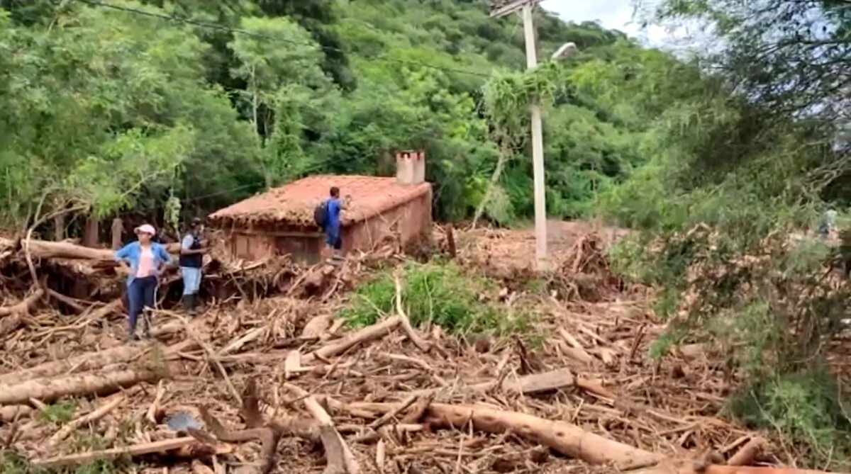 People stand on the roof of a house covered by mud in Guaraní de Timboy, Bolivia, on Feb. 22, 2022, in a still from a video. (Bolivia Civil Defense via AP/Screenshot via The Epoch Times)