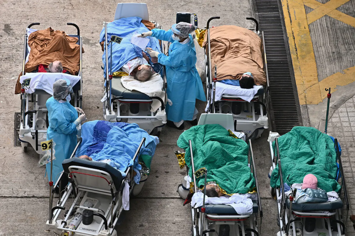 Patients lie on hospital beds at a temporary holding area outside Caritas Medical Centre in Hong Kong on Feb. 16, 2022. (Sung Pi-Lung/The Epoch Times)