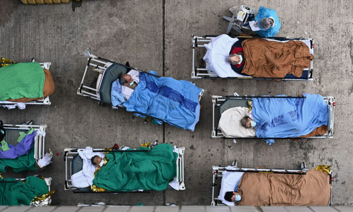 Patients lie on hospital beds at a temporary holding area outside Caritas Medical Centre in Hong Kong, on Feb. 16, 2022. (Sung Pi-Lung/The Epoch Times)