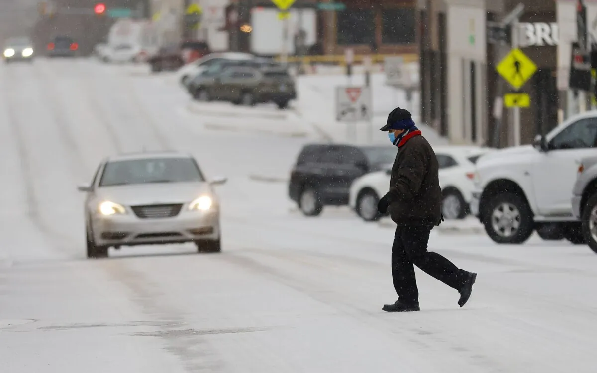 Francisco Savala crosses 15th Street (Cherry Street) between Peoria Ave. and Utica Ave. in the sleet while working at Andolini's Pizzeria, in Tulsa, Okla., on Feb. 23, 2022. (Mike Simons/Tulsa World via AP)