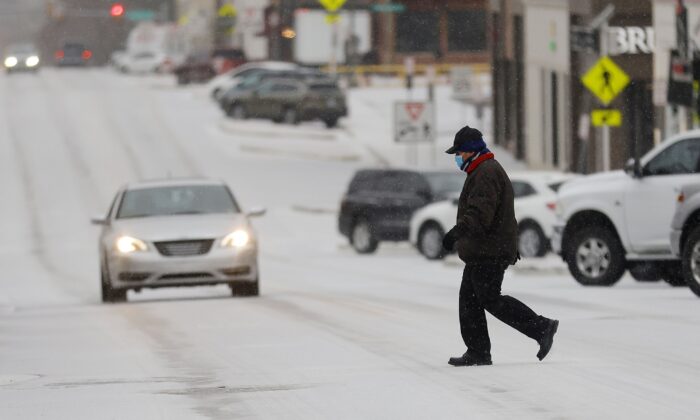 Francisco Savala crosses 15th Street (Cherry Street) between Peoria Ave. and Utica Ave. in the sleet while working at Andolini's Pizzeria, in Tulsa, Okla., on Feb. 23, 2022. (Mike Simons/Tulsa World via AP)