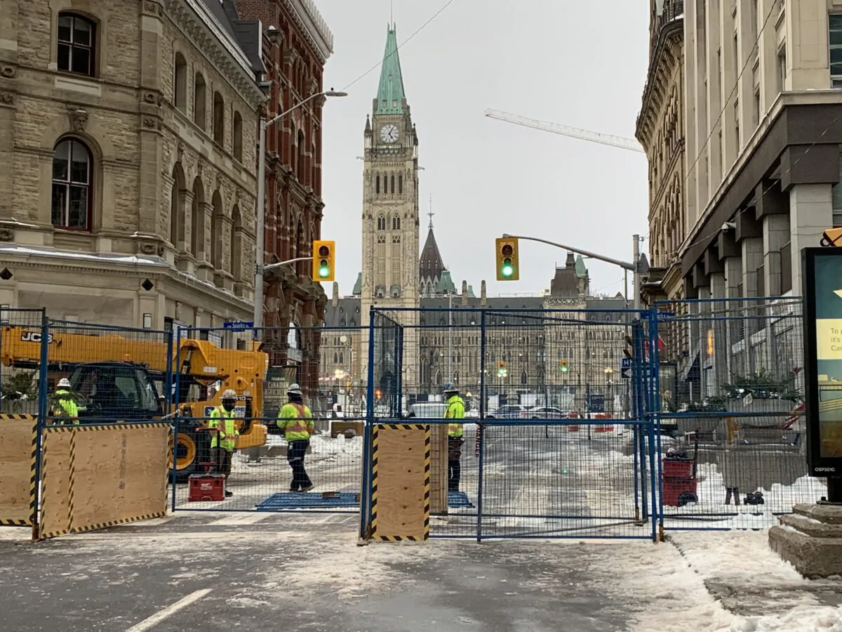 Workers build a fence on Metcalfe St. in Ottawa on Feb. 21, 2022, after the Freedom Convoy protest was cleared in the days prior. (Jonathan Ren/The Epoch Times)
