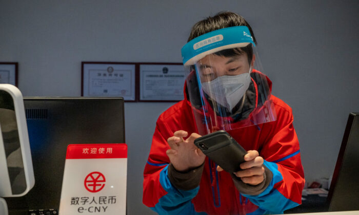 A worker at the front desk of Prince Ski Town Hotel checks the phone behind a sign saying "digital renminbi (e-CNY) is accepted" in Zhangjiakou, China, on Dec. 4, 2021. (Andrea Verdelli/Getty Images)