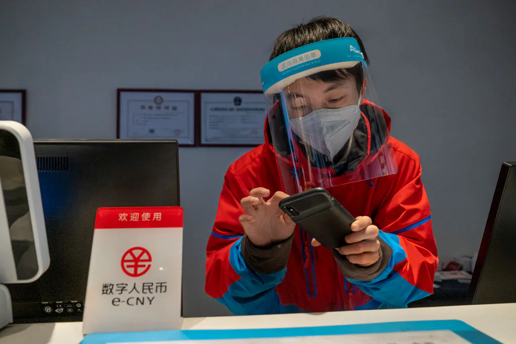 A worker at the front desk of Prince Ski Town Hotel checks the phone behind a sign saying "digital renminbi (e-CNY) is accepted" in Zhangjiakou, China, on Dec. 4, 2021. (Andrea Verdelli/Getty Images)