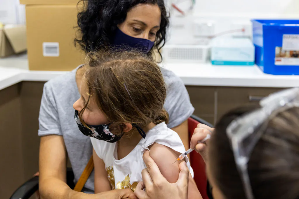 Registered nurse Emma Ahearn administers the Pfizer COVID-19 vaccine to Millie Persic sitting on the lap of mother Maria Persic in Sydney, Australia, on Jan. 11, 2022. (Jenny Evans/Getty Images)