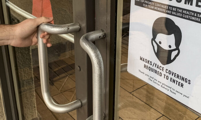 A sign for mask requirements is diplayed upon the entryway to a Corner Bakery restaurant in Irvine, Calif., on Dec. 29, 2021. (John Fredricks/The Epoch Times)