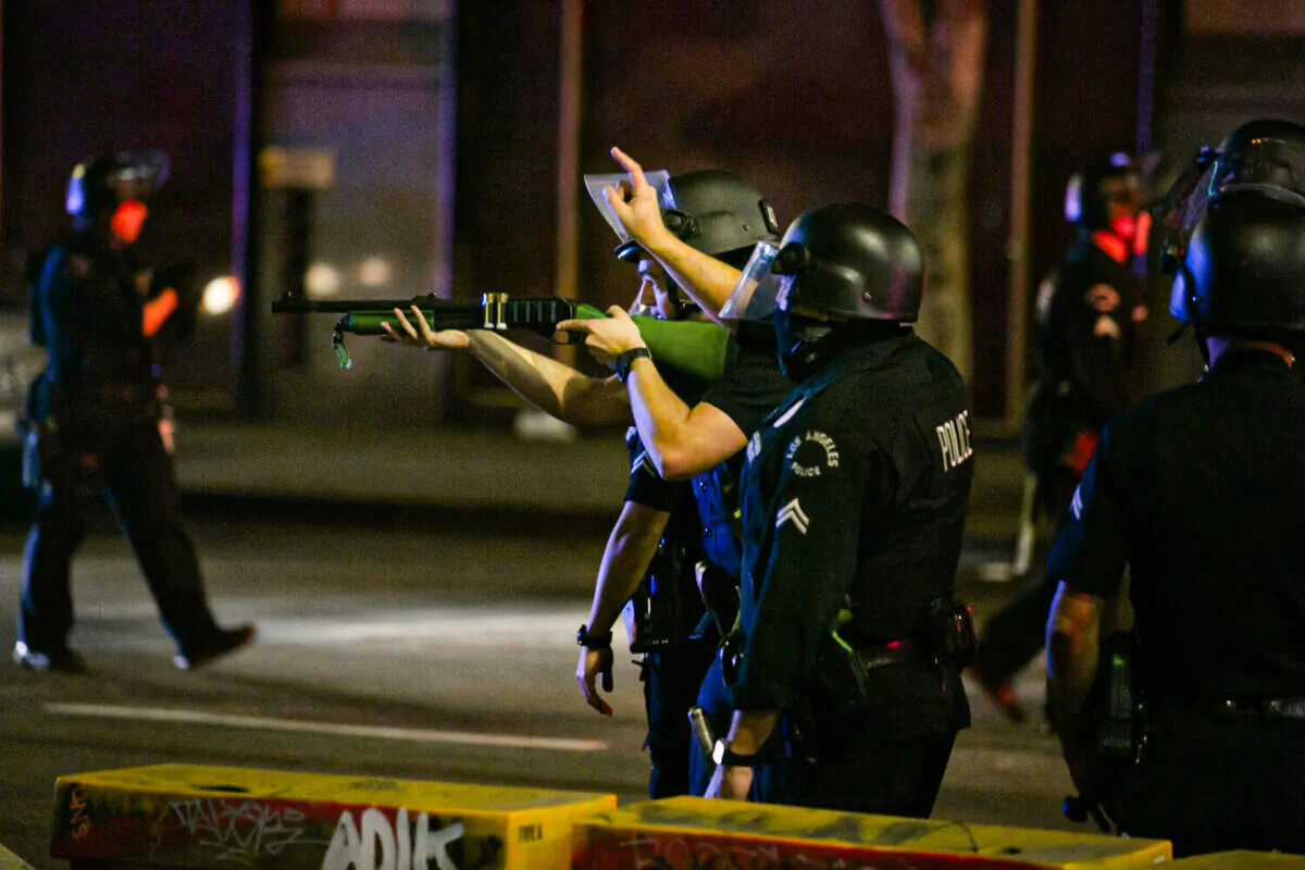 A LAPD officer aims a firearm a some people who would not disperse in downtown LA after the Dodgers win the World Series in Los Angeles on Oct. 28, 2020. (Jason Armond/Los Angeles Times/TNS)