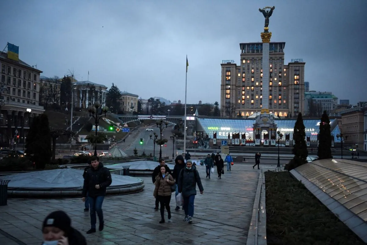 People walk in central Kyiv in front of the Independence Monument early on Feb. 24, 2022. (Daniel Leal/AFP via Getty Images)
