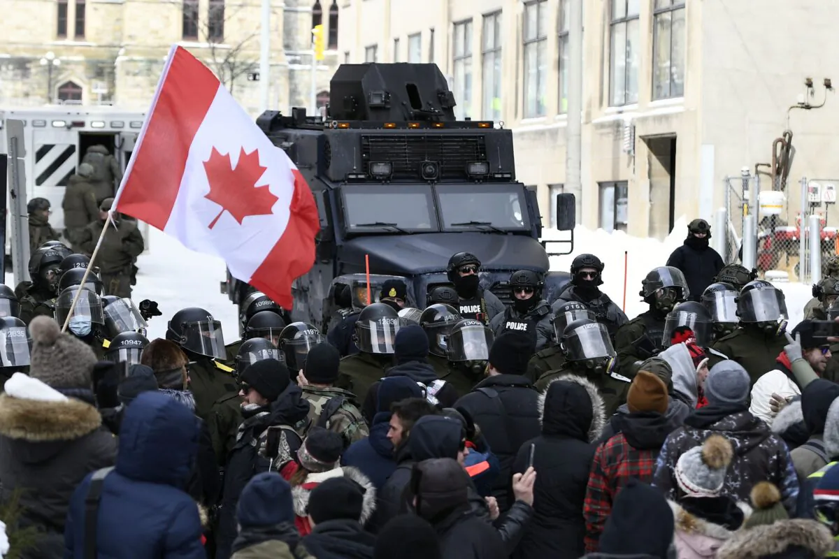 Police, including riot control officers and an armoured vehicle, take action to clear away Freedom Convoy protesters from downtown Ottawa on Feb. 19, 2022. (The Canadian Press/Justin Tang)
