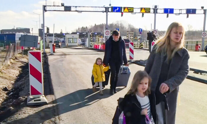 Ukrainian family walking along the road after crossing the border in Medyka, Poland, on Feb. 24, 2022, in a still from a video. (TVN via AP/Screenshot via The Epoch Times)