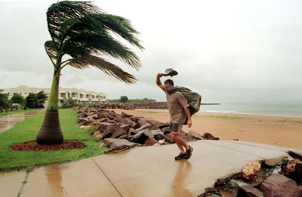 In this picture a man pushes against a cyclonic wind in Darwin on 08 December, 1998. (DAVID HANCOCK/AFP via Getty Images)