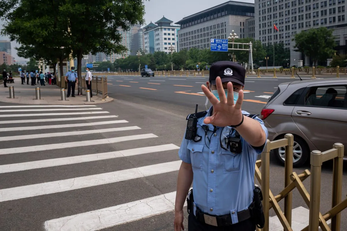 A police officer secures an area and gestures before a convoy of buses transporting delegates passes by ahead of the opening ceremony of the Chinese People's Political Consultative Conference (CPPCC) in Beijing on May 21, 2020. (Nicolas Asfouri/AFP via Getty Images)