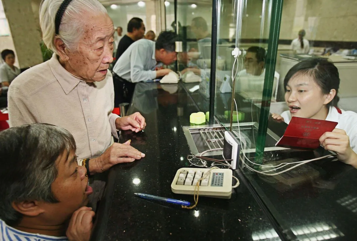 Chen Xiangying (second L), 92, draws her first pension payment from a bank on September 28, 2006 in Shanghai, China.(China Photos/Getty Images)