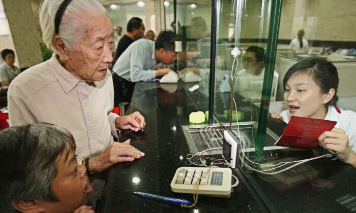 Chen Xiangying (second L), 92, draws her first pension payment from a bank on September 28, 2006 in Shanghai, China.(China Photos/Getty Images)
