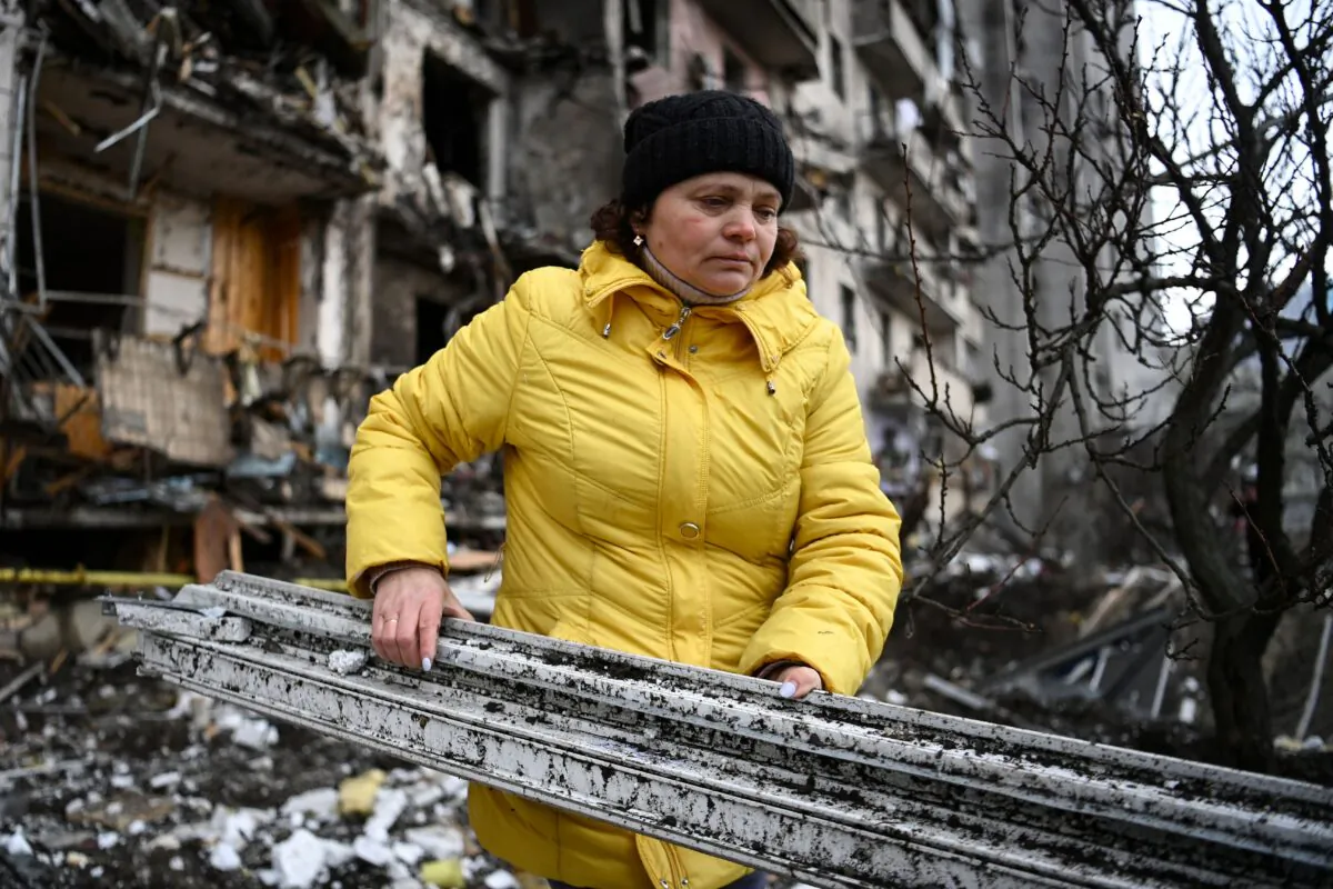 A woman clears debris at a damaged residential building at Koshytsa Street, a suburb of the Ukrainian capital Kyiv, where a military shell allegedly hit on Feb. 25, 2022. Pre-dawn blasts in Kyiv set off the second day of violence after Russian President Vladimir Putin defied Western warnings to unleash a full-scale ground invasion and air assault on Feb. 24 that quickly claimed dozens of lives and displaced at least 100,000 people. (Daniel Leal/AFP via Getty Images)