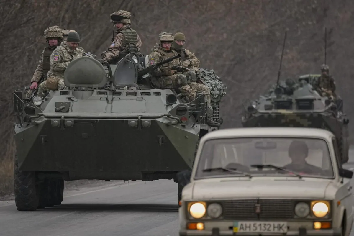 Ukrainian servicemen sit atop armored personnel carriers driving on a road in the Donetsk region, eastern Ukraine on Feb. 24, 2022. (Vadim Ghirda/AP Photo)
