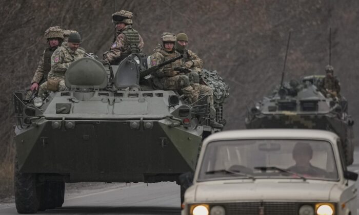 Ukrainian servicemen sit atop armored personnel carriers driving on a road in the Donetsk region, eastern Ukraine on Feb. 24, 2022. (Vadim Ghirda/AP Photo)