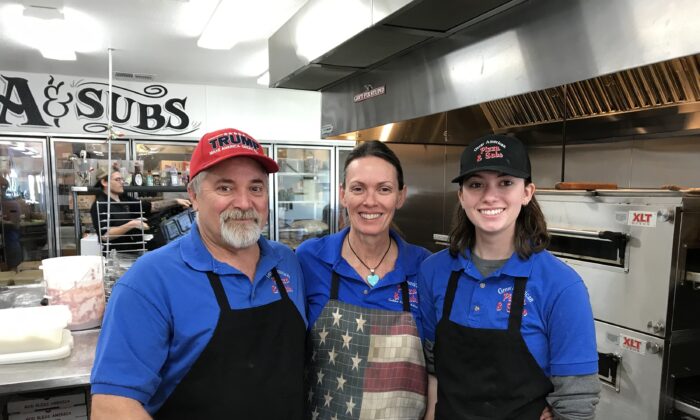 (L-R) Robert Hall, Kathleen Hall, and their daughter Gabriella pose at their restaurant, Great American Pizza and Subs, in Golden Valley, Ariz., on Feb. 24, 2022. (NTD)