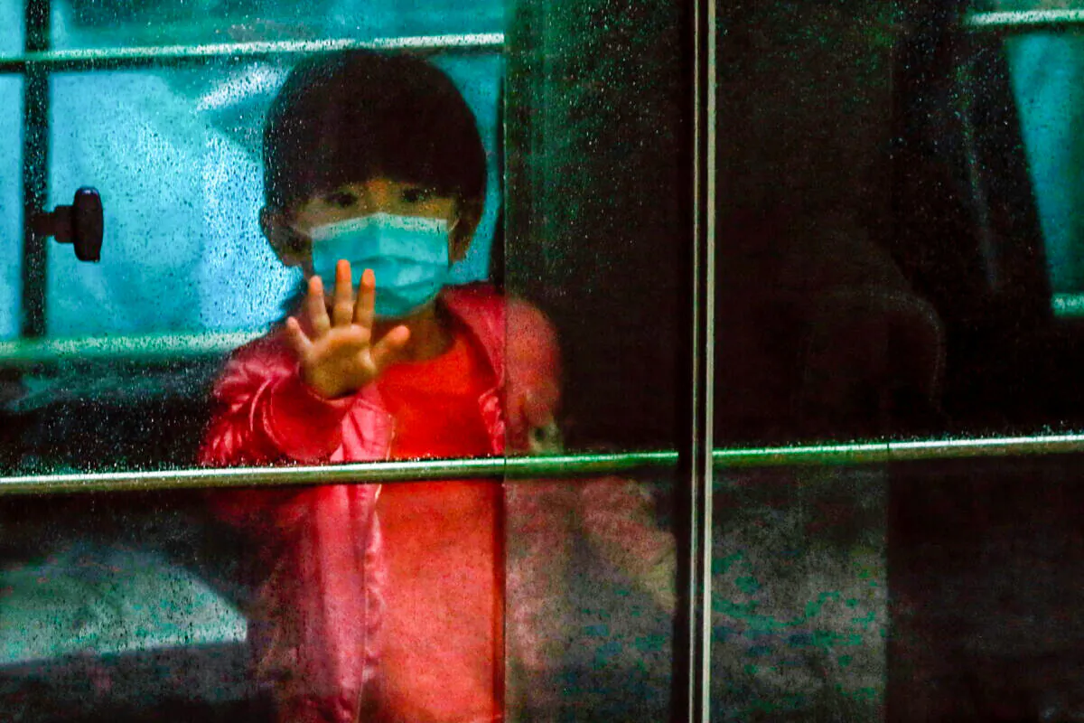 A child waves as she sits in a vehicle carrying residents evacuated from a public housing building, following the outbreak of the novel coronavirus, outside Hong Mei House, at Cheung Hong Estate in Hong Kong on Feb. 11, 2020. (Tyrone Siu/Reuters)