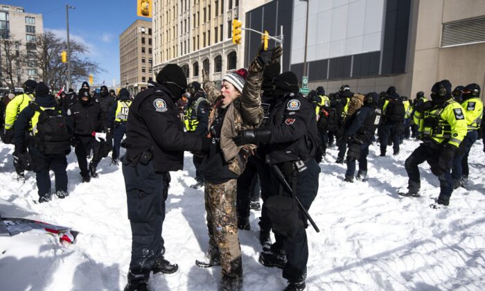 A protester sings “O Canada” as they are arrested after trying to push through a line of police officers during police action to end the Freedom Convoy protest in Ottawa on Feb. 18, 2022. (The Canadian Press/Justin Tang)