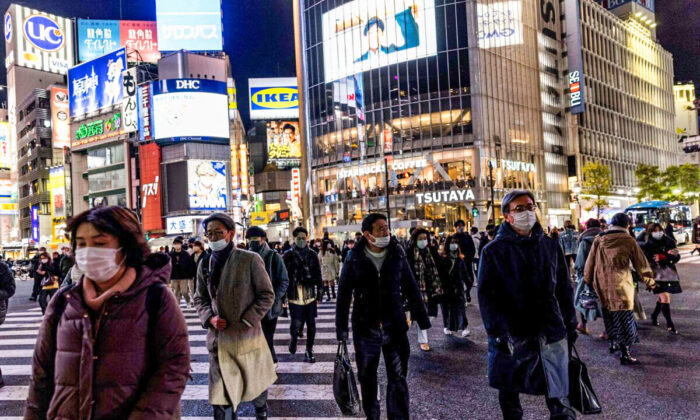 People wearing protective masks walk at Shibuya district in Tokyo on Jan. 19, 2022. (Behrouz Mehri/AFP via Getty Images)