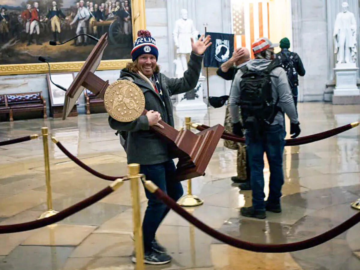 Adam C. Johnson totes House Speaker Nancy Pelosi's podium at the U.S. Capitol on Jan. 6, 2021. (U.S. Department of Justice/Screenshot via The Epoch Times)