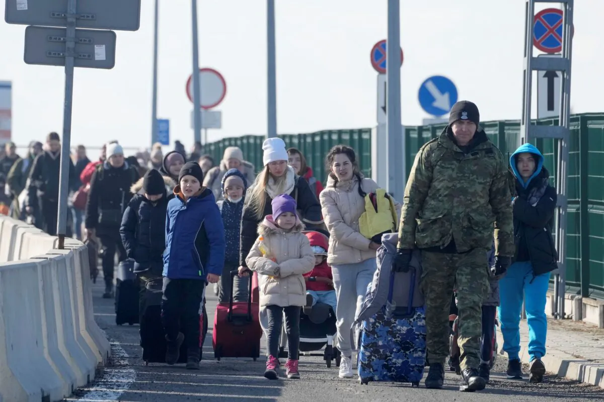 A Polish border guard assists refugees from Ukraine as they arrive to Poland at the Korczowa border crossing, Poland, on Feb. 26, 2022. (Czarek Sokolowski/AP Photo)