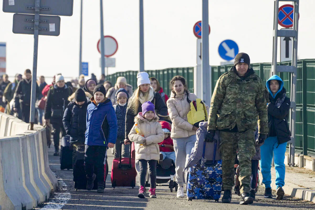 A Polish border guard assists refugees from Ukraine as they arrive to Poland at the Korczowa border crossing, Poland, on Feb. 26, 2022. (Czarek Sokolowski/AP Photo)