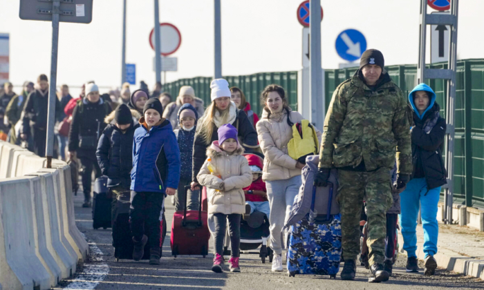 A Polish border guard assists refugees from Ukraine as they arrive to Poland at the Korczowa border crossing, Poland, on Feb. 26, 2022. (Czarek Sokolowski/AP Photo)