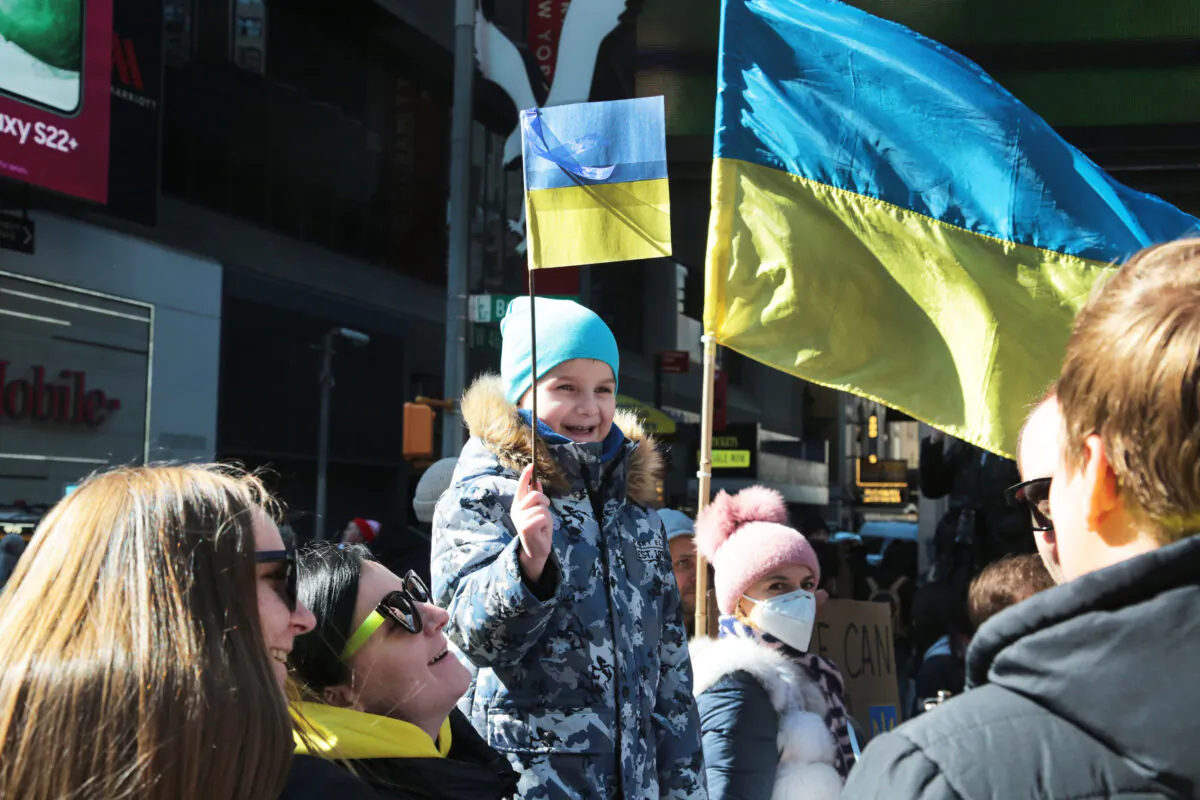 A child waves a Ukrainian flag in Times Square on Feb. 26, 2022. (Richard Moore/The Epoch Times)