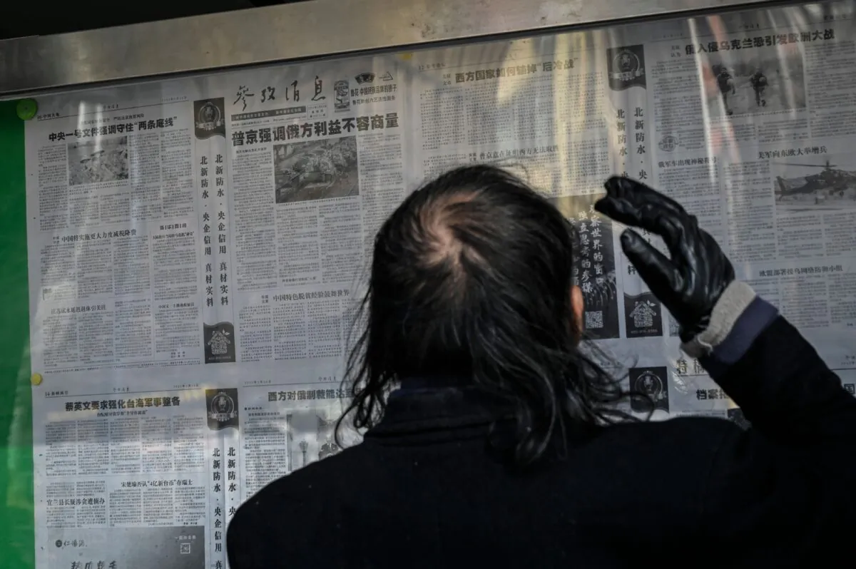 A man reads a Chinese state-run newspaper with coverage of Russia's invasion of Ukraine, that supports Russia’s actions, on a street in Beijing, China on Feb. 24, 2022. (Jade Gao/AFP via Getty Images)