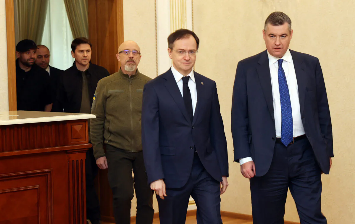 Ukrainian Defence Minister Oleksii Reznikov (4L), Russian presidential aide Vladimir Medinsky (2R) and other members of the both delegations enter a hall for the talks in Belarus' Gomel region on Feb. 28, 2022, following the Russian invasion of Ukraine. (Sergei Kholodilin/AFP via Getty Images)