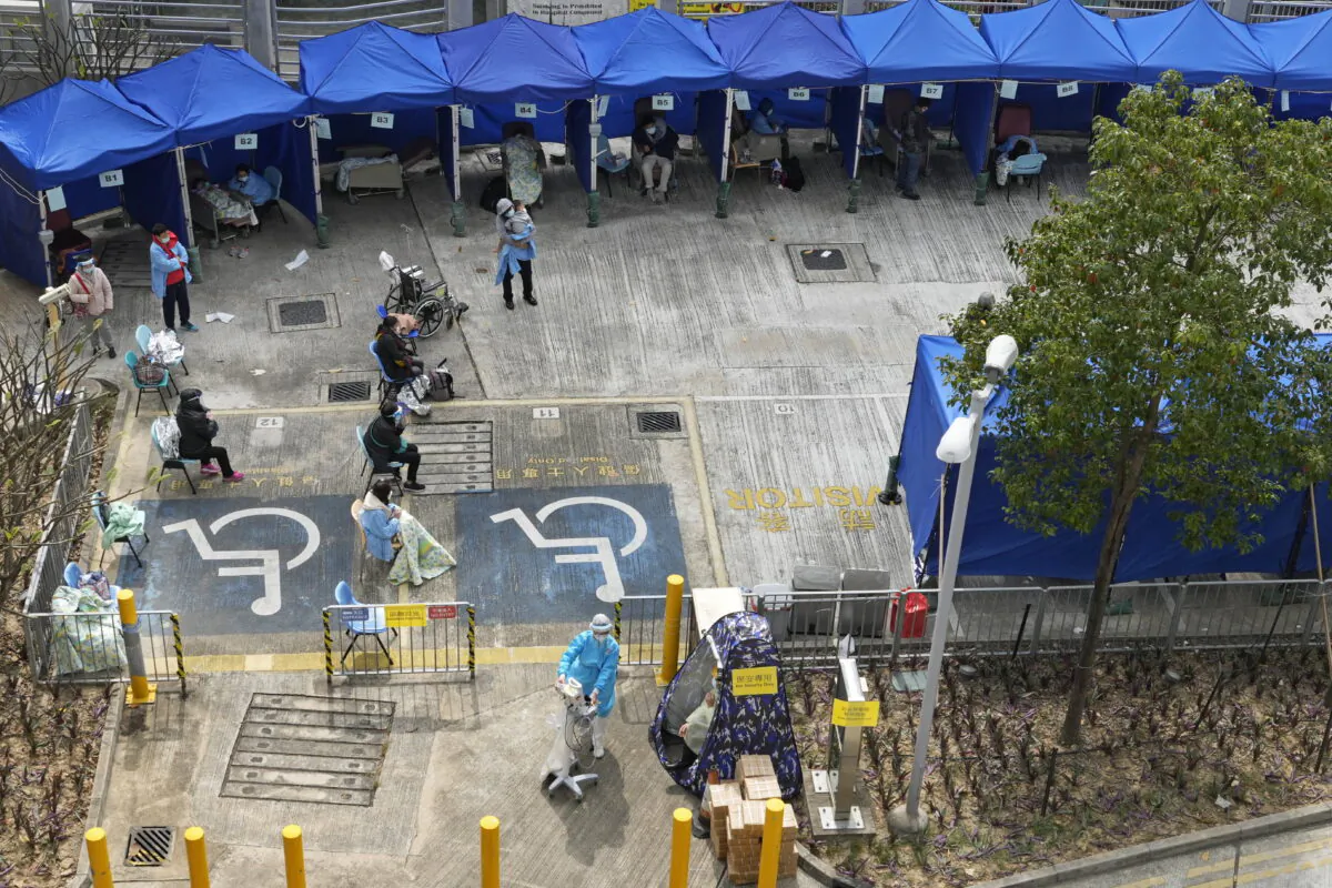 People including current hospital patients showing COVID-19 symptoms wait at a temporary holding area outside Caritas Medical Centre in Hong Kong on Feb. 16, 2022. (Vincent Yu/AP Photo)