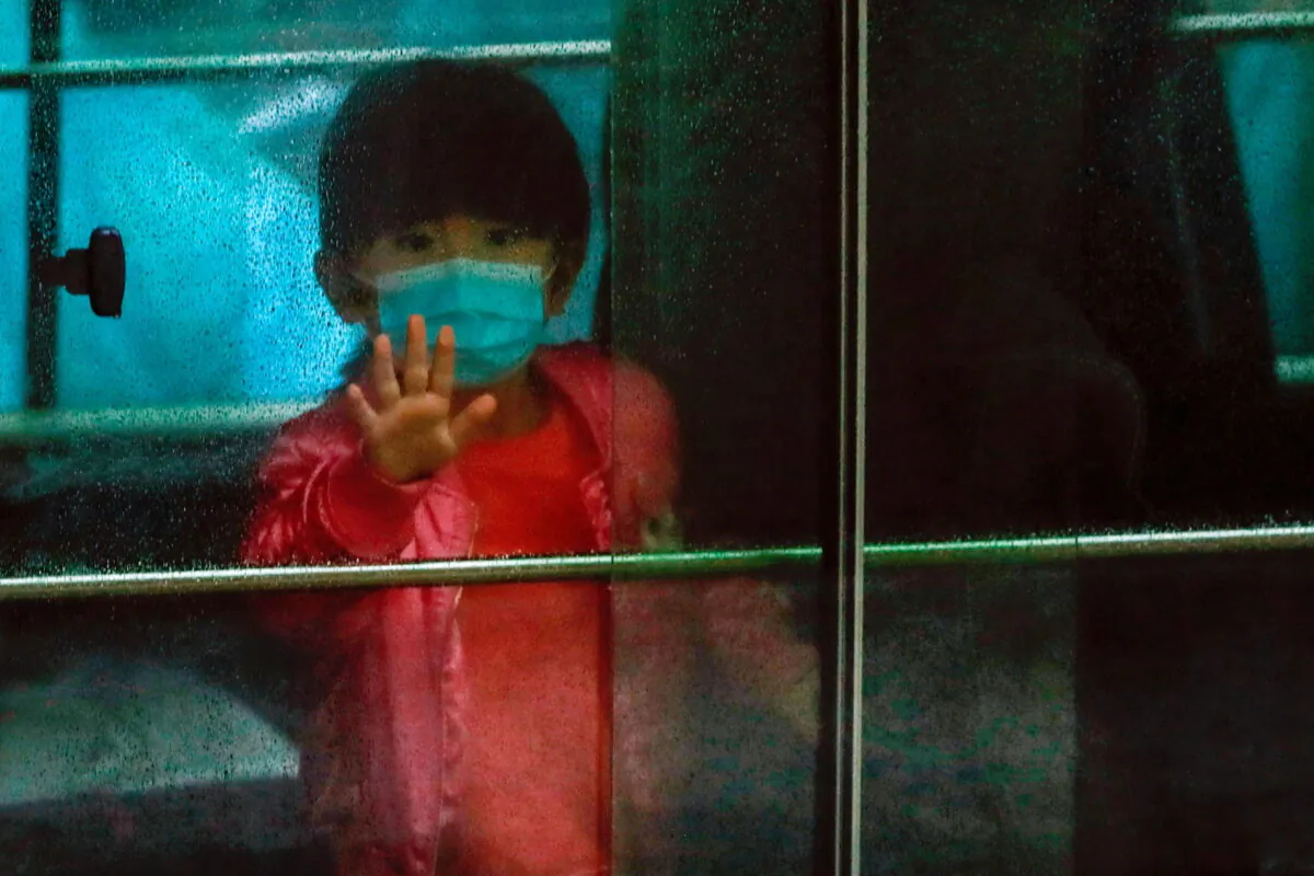 A child waves as she sits in a vehicle carrying residents evacuated from a public housing building, following the outbreak of the novel coronavirus, outside Hong Mei House, at Cheung Hong Estate in Hong Kong on Feb. 11, 2020. (Tyrone Siu/Reuters)