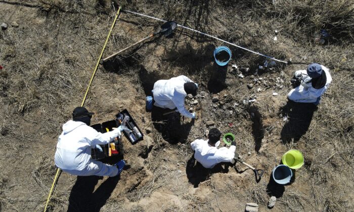 Forensic technicians excavate a field on a plot of land referred to as a cartel "extermination site" where burned human remains are buried, on the outskirts of Nuevo Laredo, Mexico on Feb. 8, 2022. (Marco Ugarte/AP Photo)