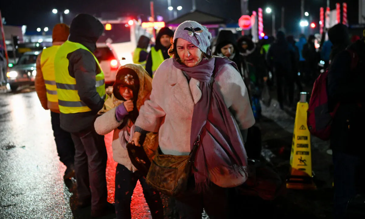Refugees from Ukraine walk along a road after crossing the Moldova–Ukrainian border's checkpoint near the town of Palanca on March 1, 2022. (Nikolay DOYCHINOV/AFP)