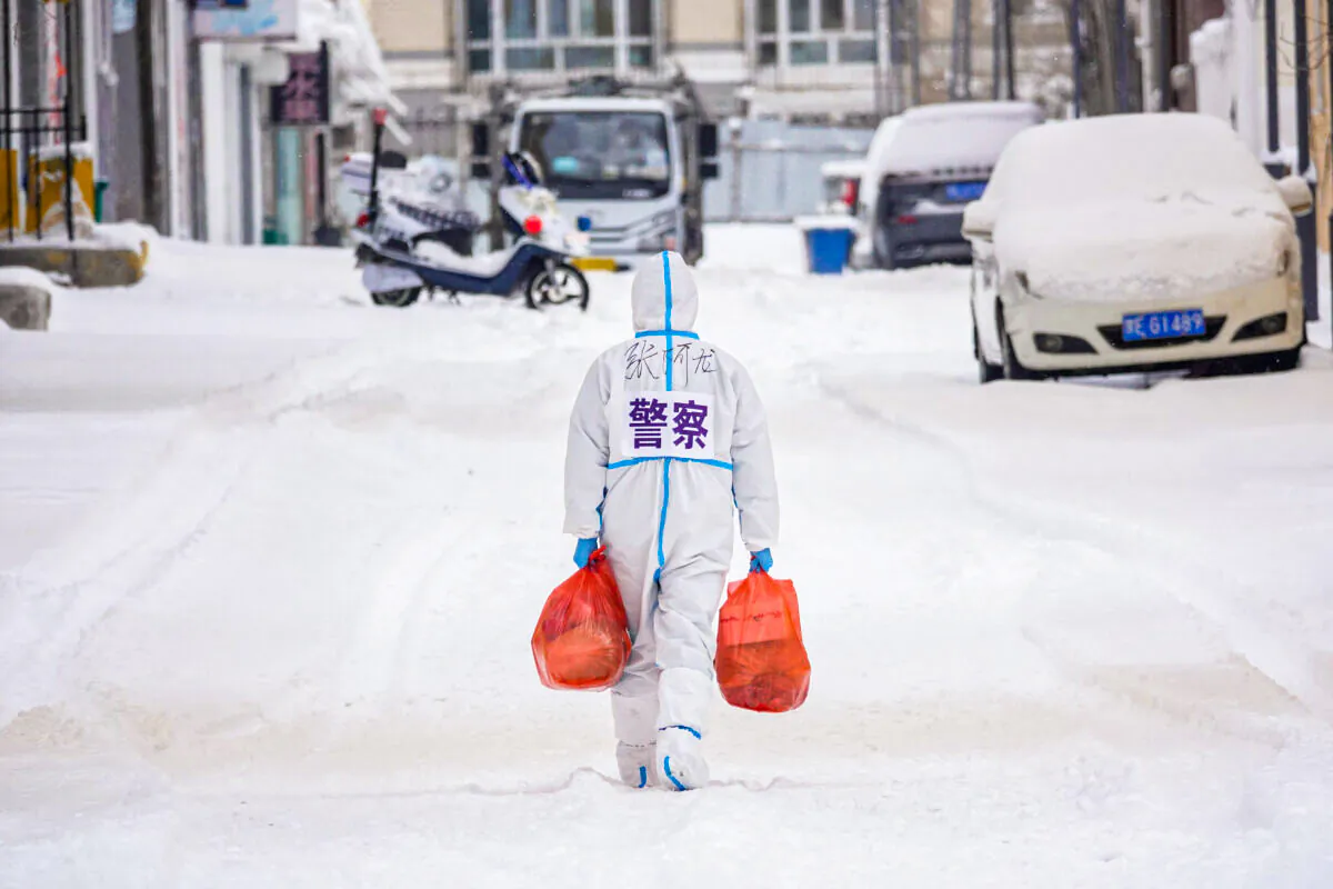 A police officer wearing personal protective equipment (PPE) carries food and daily supplies that will be distributed to residents at a restricted residental area due to the spread of the COVID-19 coronavirus in Manzhouli in China's northern Inner Mongolia region on March 15, 2022. (STR/AFP via Getty Images)