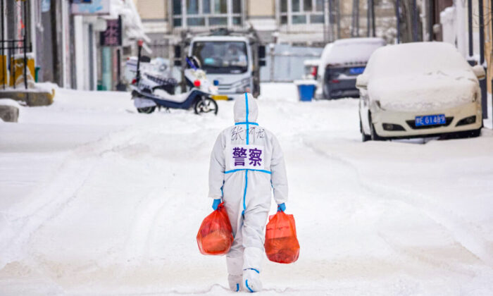 A police officer wearing personal protective equipment (PPE) carries food and daily supplies that will be distributed to residents at a restricted residental area due to the spread of the COVID-19 coronavirus in Manzhouli in China's northern Inner Mongolia region on March 15, 2022. (STR/AFP via Getty Images)