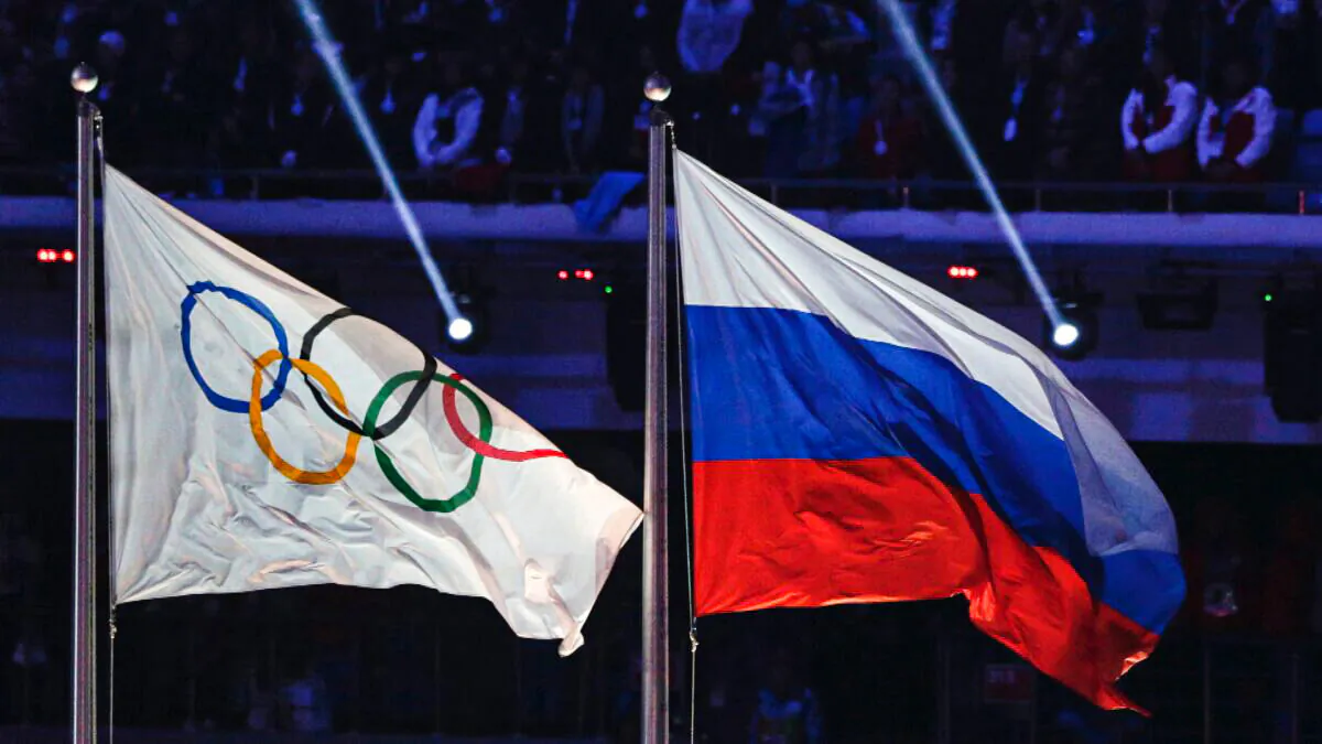 The Russian national flag (R) flies after it is hoisted next to the Olympic flag during the closing ceremony of the 2014 Winter Olympics in Sochi, Russia, on Feb. 23, 2014. (Matthias Schrader/AP Photo)