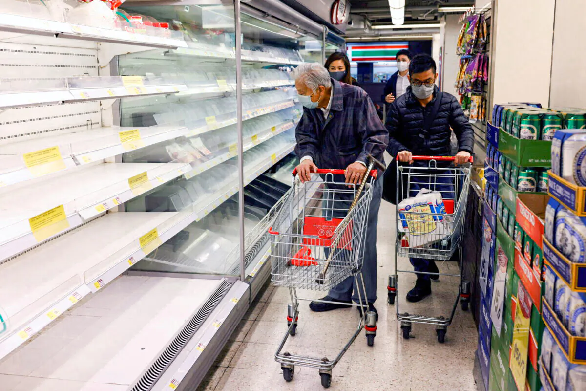 Customers wearing masks shop in front of partially empty shelves at a supermarket during the COVID-19 outbreak in Hong Kong, on Feb. 28, 2022. (Tyrone Siu/Reuters)