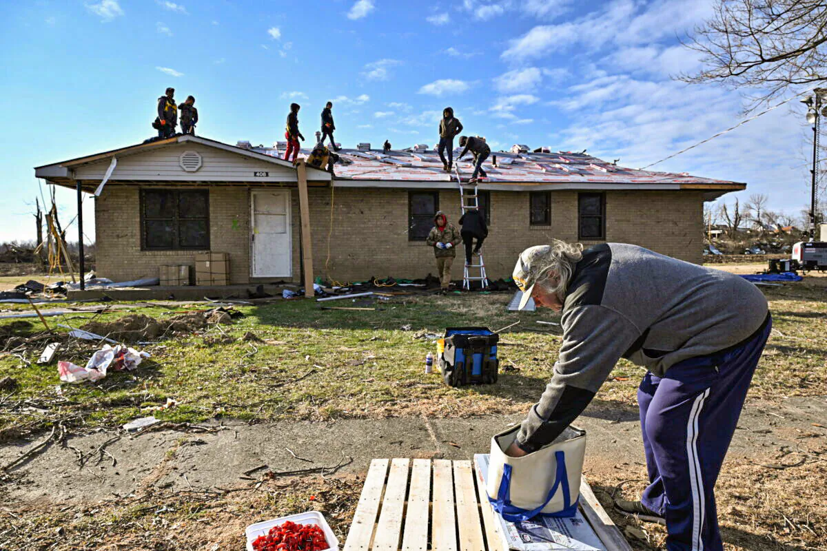 Charles Carmickle reaches to grab sandwiches to give away to nearby construction workers repairing a home after tornadoes ripped through several U.S. states in December in Mayfield, Ky., on Jan. 28, 2022. (Jonathan Cherry/Reuters)